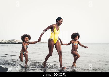 Happy African family on the beach during summer holidays - Afro American people having fun on vacation time