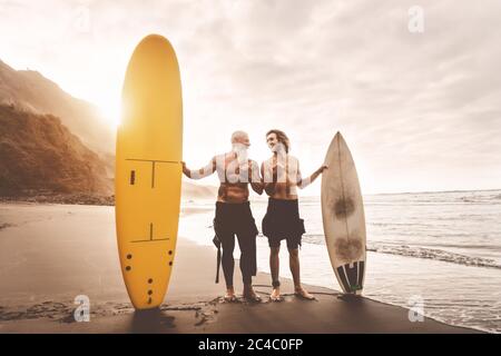 Happy friends surfing together on tropical ocean - Sporty people having fun during vacation surf day Stock Photo