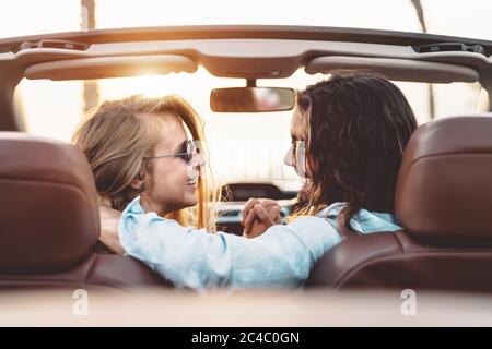 Happy young couple doing road trip in tropical city - Travel people having tender moments in trendy convertible car while discovering new places Stock Photo