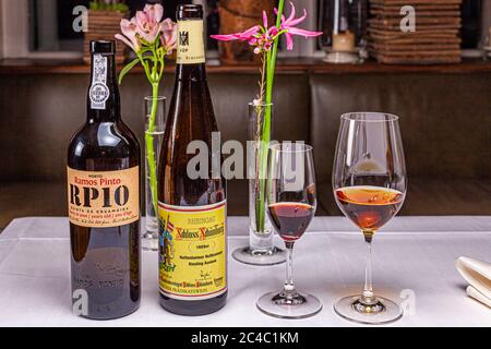 A bottle of Ramos Pinto RP10, a ten-year-old tawny port from Quinta de Ervamoira, and a bottle of 1989 Hattenheimer Nussbrunnen Riesling Auslese from the Schloss Schönborn estate stand next to two filled glasses on a laid table in the Hotel and Restaurant Kronenschlösschen in Hattenheim, Eltville am Rhein, Hesse, Germany. The Auslese accompanies the dessert "Die Rose des Jahres" ("the rose of the year") by star chef Rodolfo Guzmán (Restaurant Boragó, Santiago de Chile). The port is the digestif. Both belong to the gala dinner Guzmán gives with host chef Simon Stirnal on 25 February 2017. Chris Stock Photo