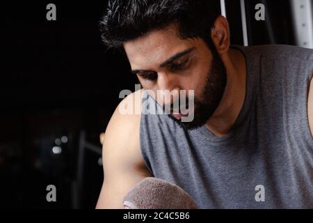 closeup of Beard man cleaning sweat with towel after workout ,Man tired after workout in full Sweating Stock Photo