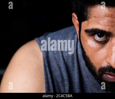 extreme closeup of half face of beard man with anger on eyes Stock Photo