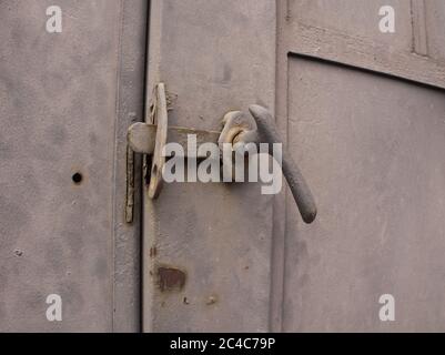 Door latch on and abandoned building grey door up close detail Stock Photo