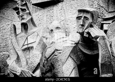 The exterior of Antoni Gaudi's Sagrada Familia is adorned with remarkable sculptures, like this sad man and skeletal woman Stock Photo
