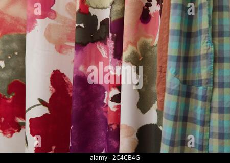 Multi-colored abstract floral and plaid fabric samples hanging vertically. Stock Photo
