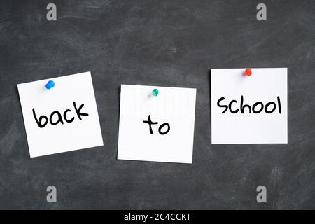 Back to school concept. Post it note pin stickers with text back to school and on black board background. Stock Photo