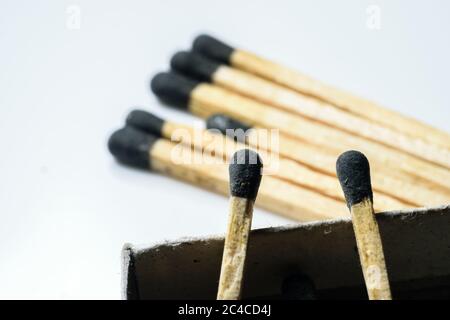 Two match sticks in focus over the edge of a match box and multiple match sticks laying on the floor in the background. White background Stock Photo