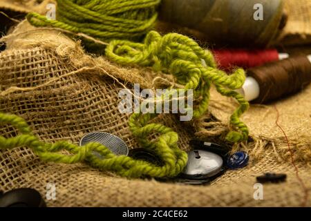 Various buttons and multicolored threads on coarse-textured burlap. Close up Stock Photo