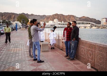 Muscat / Oman - February 15, 2020: group of Muslim male friends enjoy leisure time taking photos in the Corniche of Muscat near Mutrah Souq Stock Photo