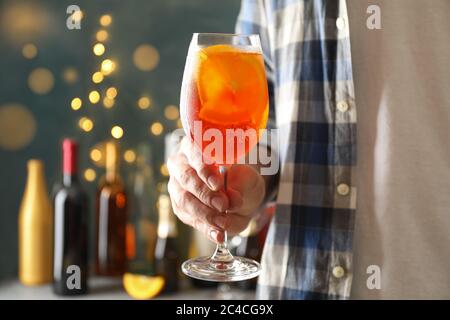 Male hand holds glass of aperol spritz. Making summer cocktail