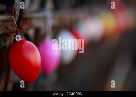 Colorfully colored Easter eggs hang in a row on an old garden fence, Bremen, Germany Stock Photo