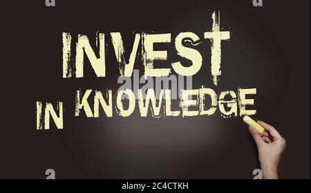 Invest in Knowledge writing, written with Chalk on Blackboard. Education and business concept Stock Photo