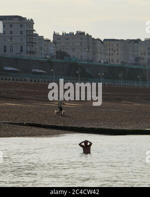 Brighton UK 26th June 2020 - A swimmer emerges from the sea in Brighton this morning on another beautiful hot sunny day . Crowds flocked to Brighton yesterday which was the hottest day of the year so far  : Credit Simon Dack / Alamy Live News Stock Photo