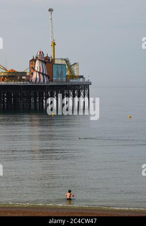 Brighton UK 26th June 2020 - A swimmer enters the sea in Brighton this morning on another beautiful hot sunny day . Crowds flocked to Brighton yesterday which was the hottest day of the year so far  : Credit Simon Dack / Alamy Live News Stock Photo