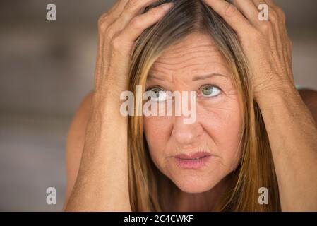 Portrait attractive mature woman, stressed, anxious, scared, unhappy frightened, hands covering head, blurred background. Stock Photo