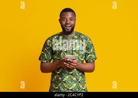 Excited black guy holding modern mobile phone Stock Photo