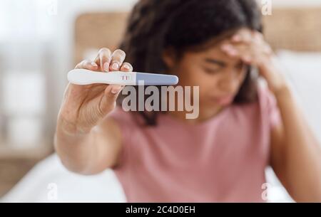Upset black woman holding positive pregnancy test Stock Photo