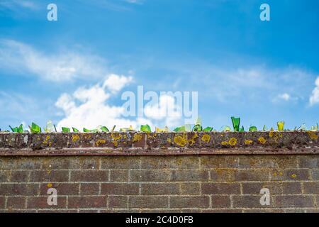 A boundary wall with broken glass as a deterrent against burglars or ...