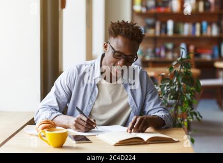 Young African American man studying in modern cafe Stock Photo