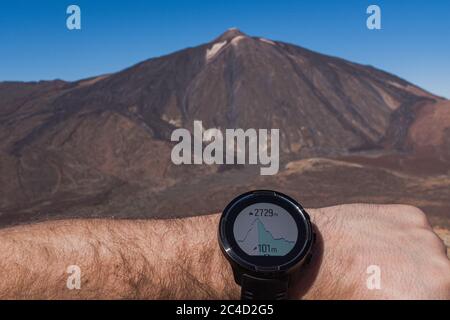 Runner checking progress on smart watch. Volcano on background Stock Photo