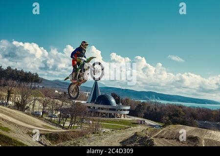 racer on mountain bike participates in motocross race, takes off and jumps on springboard, against the blue sky. Close-up. concept of extreme rest Stock Photo