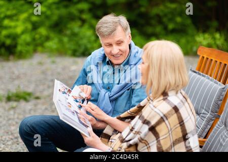 Man in camping lounge chair fishing and using digital tablet stock