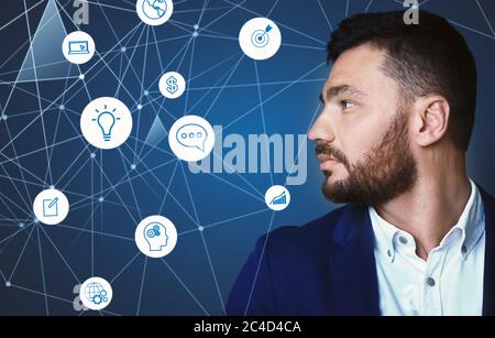 Handsome young man with beard looks away at abstract hologram icons Stock Photo
