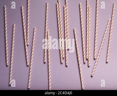 Closeup of the scattered striped, retro paper straws on a light purple surface Stock Photo