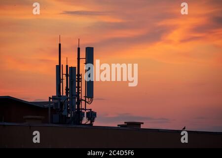 Phone tower antennas silhouette on sunset background Stock Photo