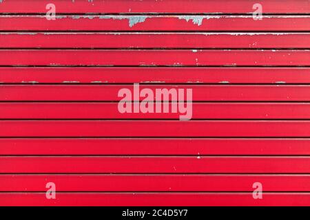 Red metal shutter texture. Architectural detail, closeup. Material background. Paint peeling and ruined by time and bad weather. Stock Photo