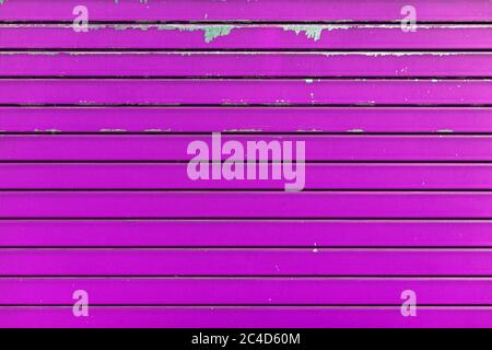 Magenta metal shutter texture. Architectural detail, closeup. Material background. Paint peeling and ruined by time and bad weather. Stock Photo