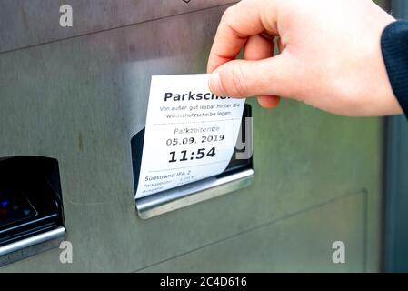 FEHMARN, GREECE - Sep 05, 2019: A hand pulls a parking ticket out of a parking ticket machine, on which it is noted when the parking time ends and whe Stock Photo