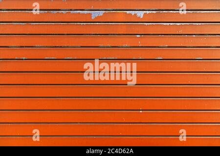 Orange metal shutter texture. Architectural detail, closeup. Material background. Paint peeling and ruined by time and bad weather. Stock Photo