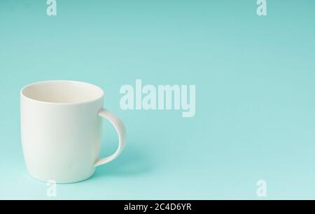 white mug for hot drinks, on a blue background, copyspace, horizontal position Stock Photo