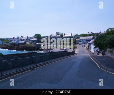 View down main street of this small fishing village Moelfre Isle of Anglesey North Wales UK with rowing boats pulled onto pebbly beach on a lovely sum Stock Photo