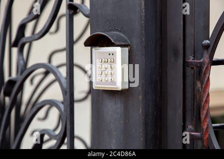 electronic security lock for access with buttons for entering the installed password on the iron forged gate, side view close up safety device. Stock Photo