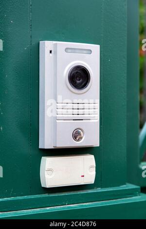 an intercom with a video camera and a microphone for voice communication with a card reader for access by a key card is installed on a green iron gate Stock Photo