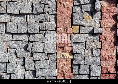 granite blocks of different sizes paved on the wall with a stone architectural texture. Stock Photo