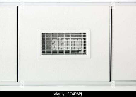 tile ceiling with square white gypsum tiles with a ventilation grille in the room close up. Stock Photo