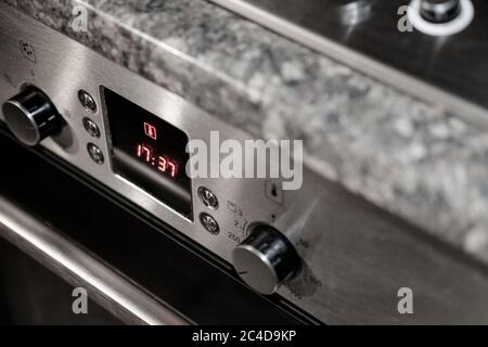 Isolated view of a modern electric oven showing the central digital display. The oven is turned on and the retractable knobs are seen. Stock Photo