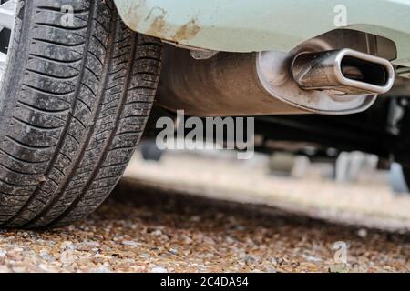 Ground level view of a new car, showing the rear tyre and tread together with its exhaust system and composite rear bumper. Stock Photo