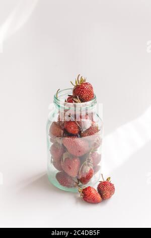 Fresh strawberries in a glass jar on white background. Stock Photo