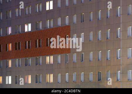 Pattern of rows of window frames, some illuminated, some in darkness, at night. Stock Photo