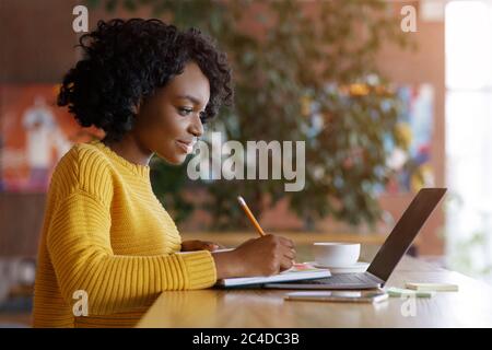 Young black lady looking for job online at cafe