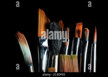 Paint brushes of different size are kept side by side in a dark background Stock Photo