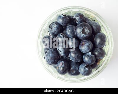 Fresh blueberries in a glass ramekin dish isolated on a white background with copy space