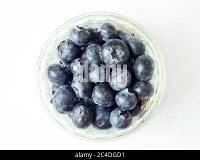 Fresh blueberries in a glass ramekin dish centred on a white background