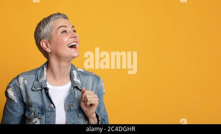 Great Offer. Excited Middle-Aged Lady Looking At Copy Space On Yellow Background Stock Photo