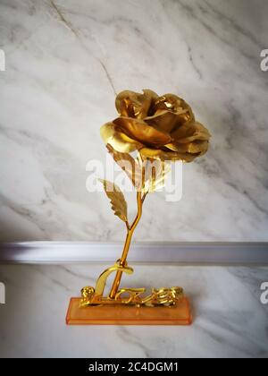 Closeup shot of a golden rose figurine on a marble rock background Stock Photo