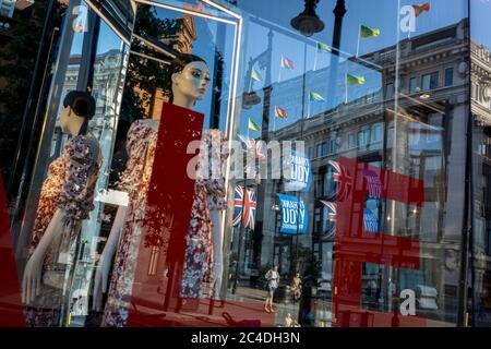 With a further 149 reported dying from Coronavirus in the last 24hrs, taking the UK death toll to 43,320, shoppers are distorted through the Sale window at the 'Zara' Oxford Street store which has recently re-opened foir business after easing of government lockdown rules. Union Jack flags hang alongside Thank You banners in support of NHS (National Health Service) key workers during the Covid pandemic, on 25th June 2020, in London, England. Stock Photo